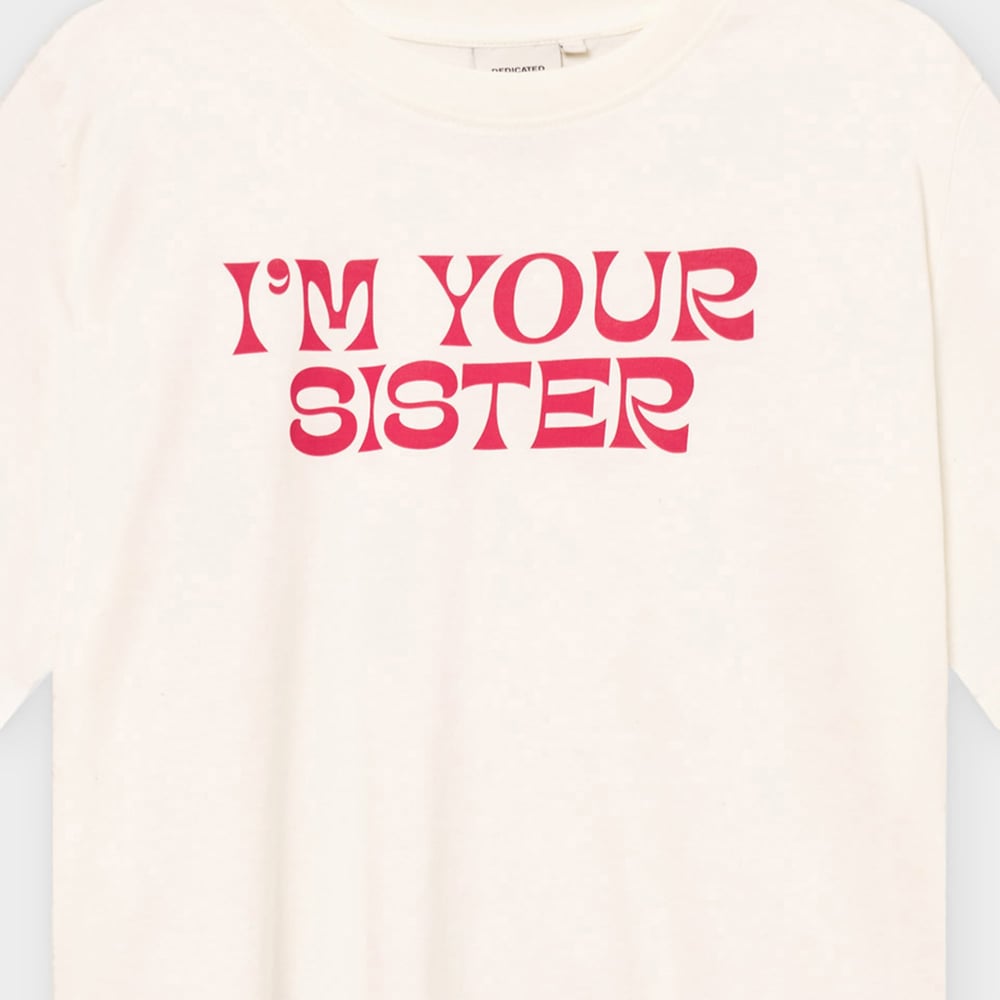 Close-up of the off-white T-shirt Vadstena Sister, showing the bold 'I'M YOUR SISTER' print in a pink-red retro font.