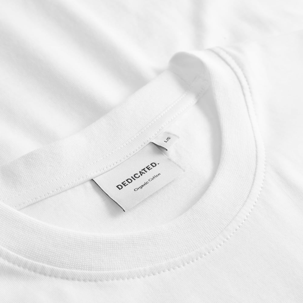 Close-up of the off-white T-shirt Stockholm Beach Habitat's collar, showing the Dedicated brand label.
