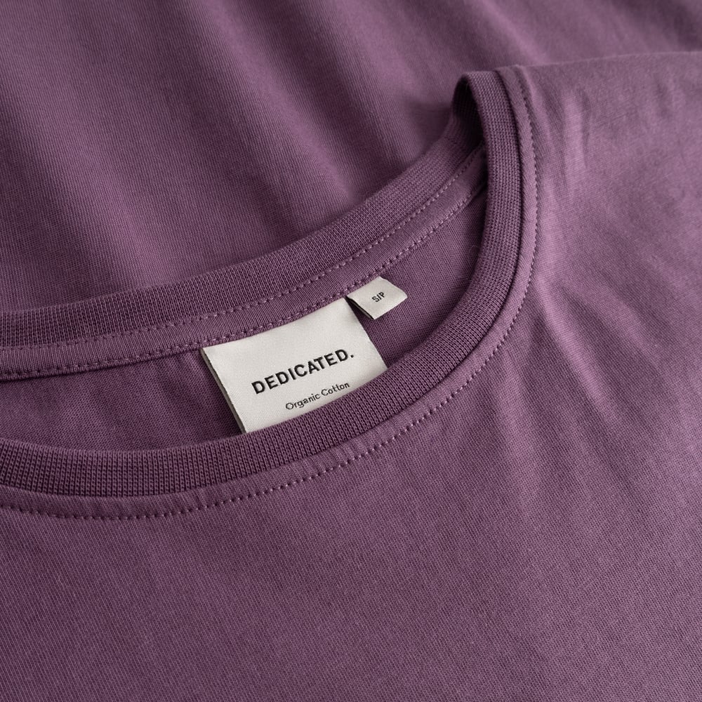 A detailed close-up of the ribbed crew neck collar and brand label on the berry purple T-shirt Visby.