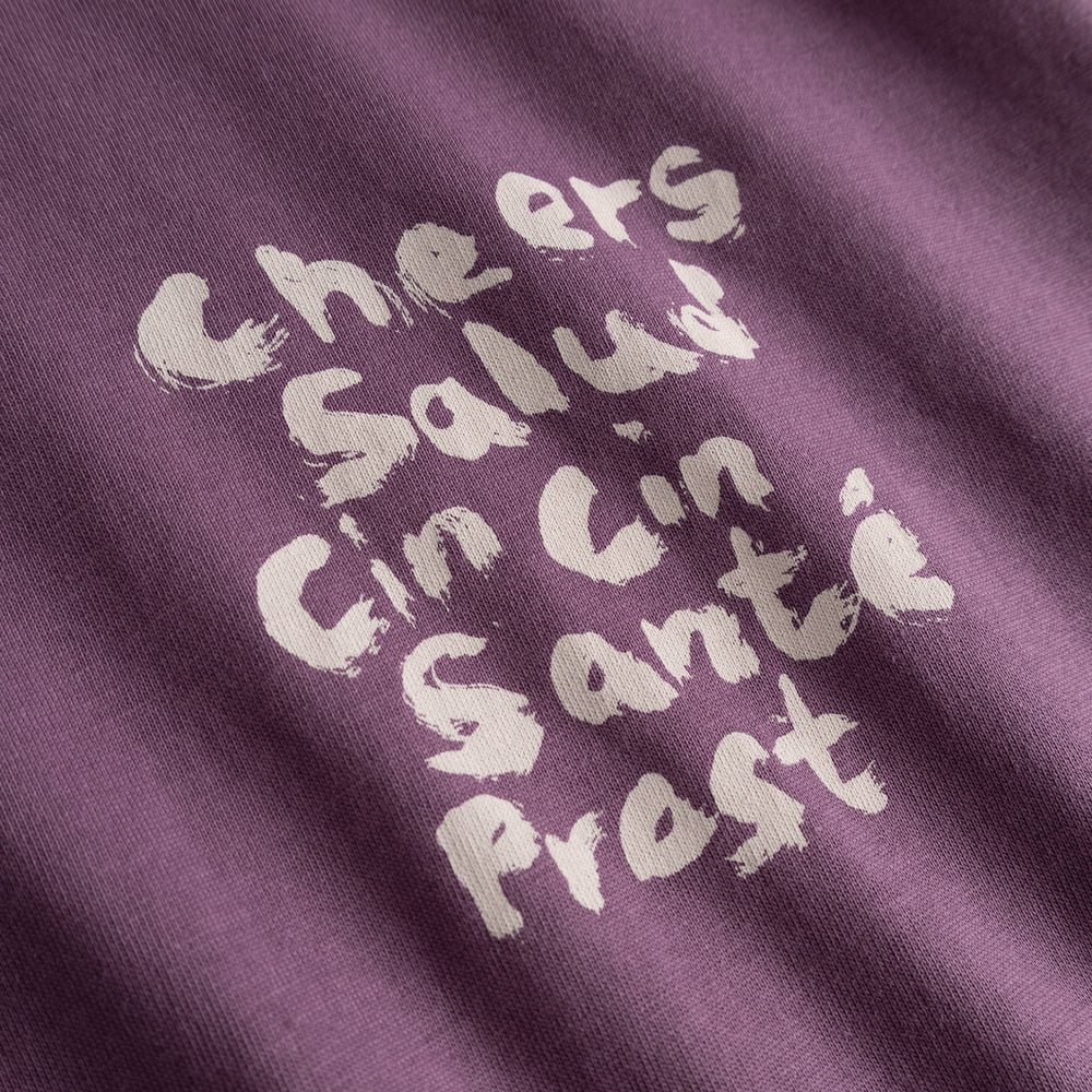 Detailaufnahme des „Cheers Salud Cin Cin Santé Prost“-Aufdrucks auf dem beerenfarbenen Stockholm T-Shirt.