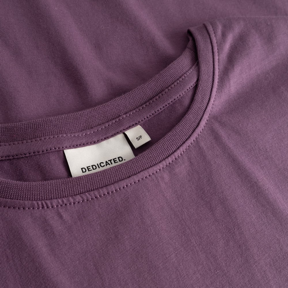 Detailed shot of the T-shirt Visby Base in Berry Purple, showing the finely ribbed crew neck and the classic Dedicated label.