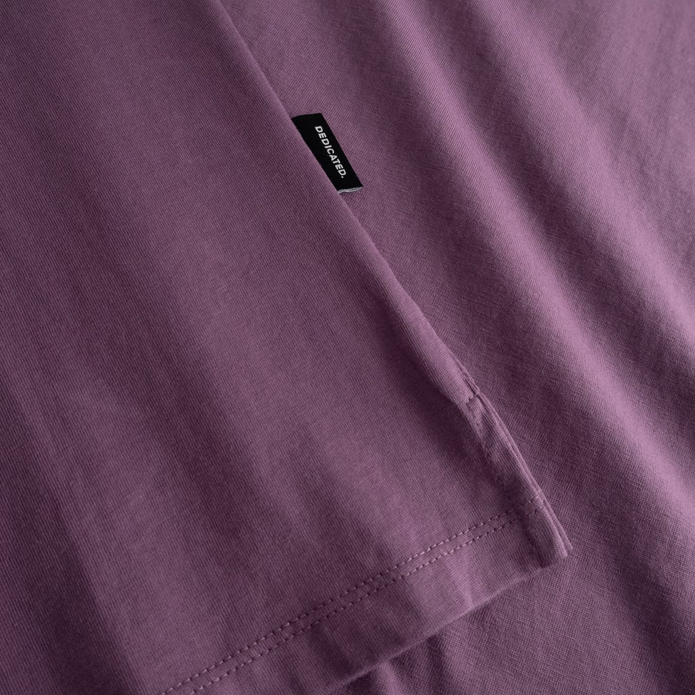 Close-up of the folded sleeve, side slit, and brand tag on the T-shirt Visby Base in a rich Berry Purple hue.