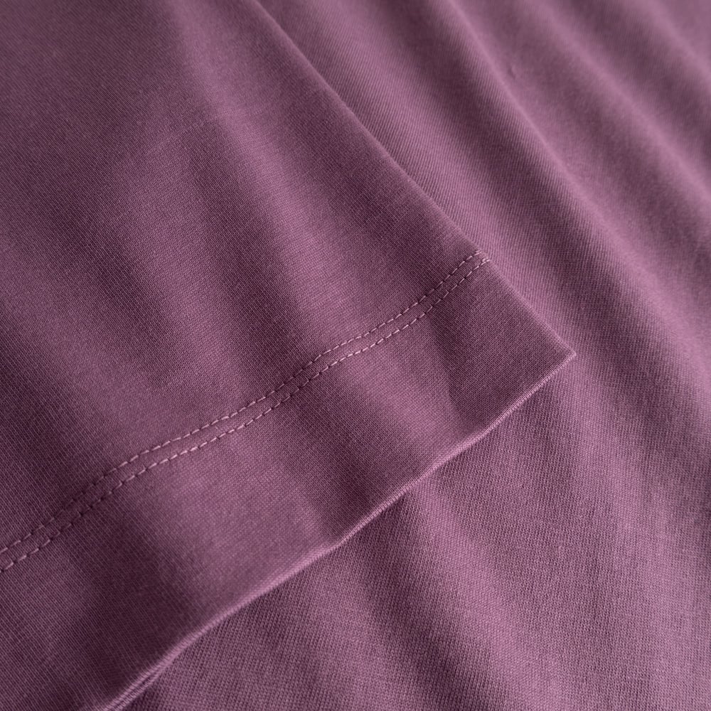 A close-up of the T-shirt Vadstena Base in Berry Purple highlighting the soft organic cotton and the sleeve's fine stitching.