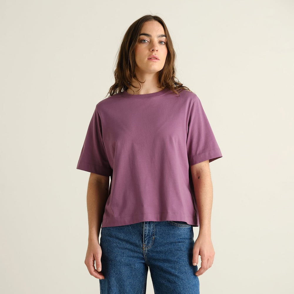 Model seen from the front wearing the relaxed-fit T-shirt Vadstena Base in Berry Purple with classic blue jeans.
