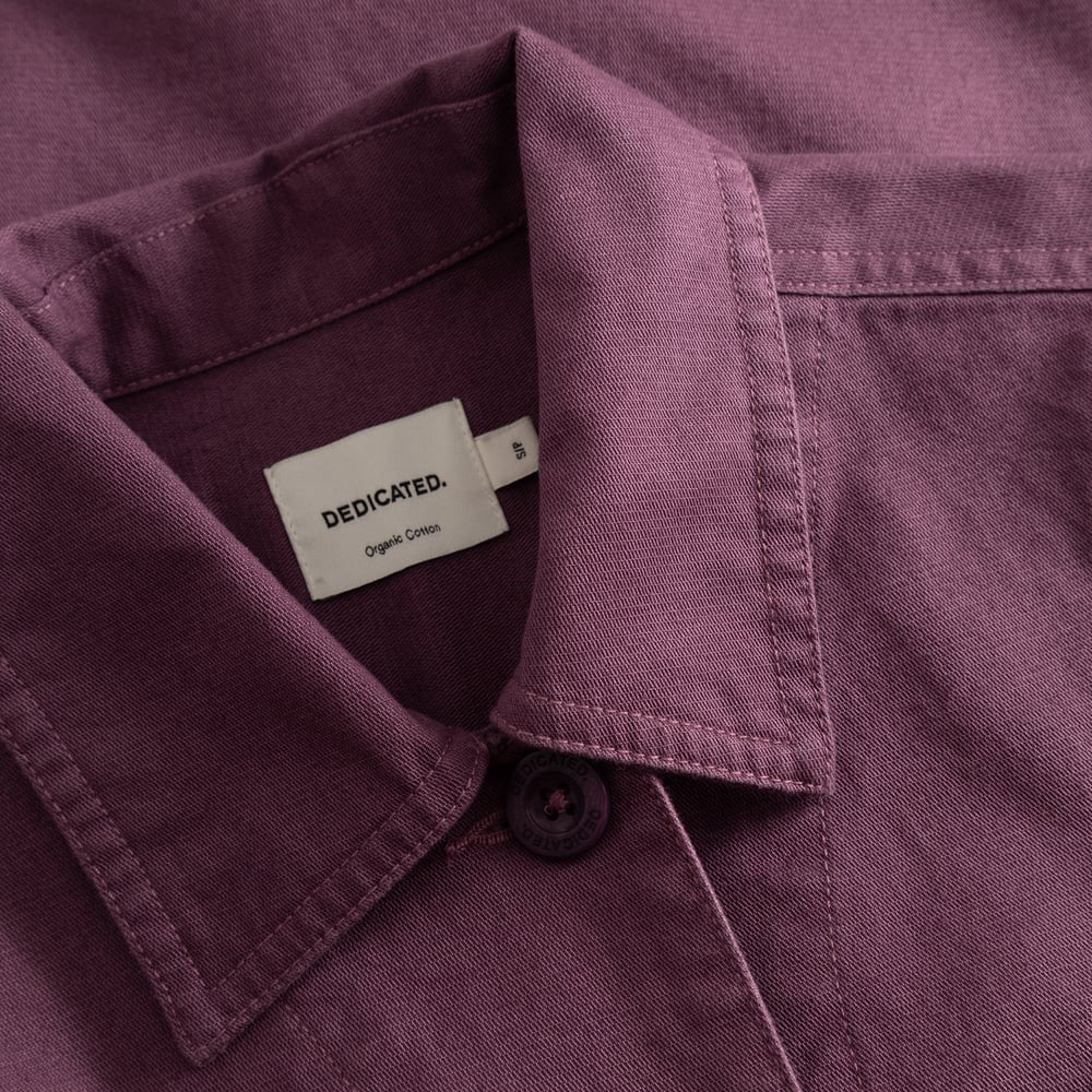 Detaljbild av kragen, tyget och märkesetiketten på jackan Stiby Berry Purple.