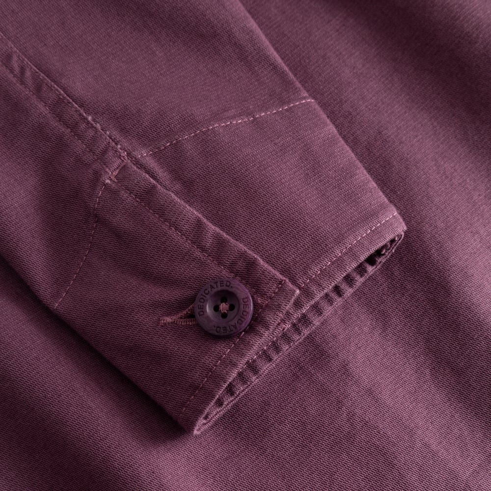 Närbild på manschetten på jackan Stiby Berry Purple som visar det mjuka manchestertyget och en knapp med logga.