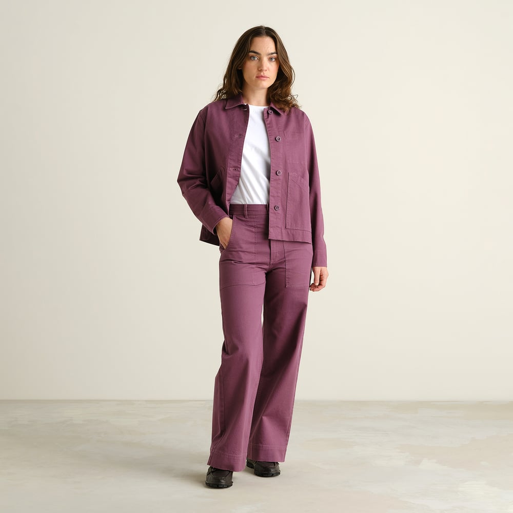 Modell i Workwear Pants Vara med vida ben i Berry Purple, med matchande jacka och vit t-shirt.