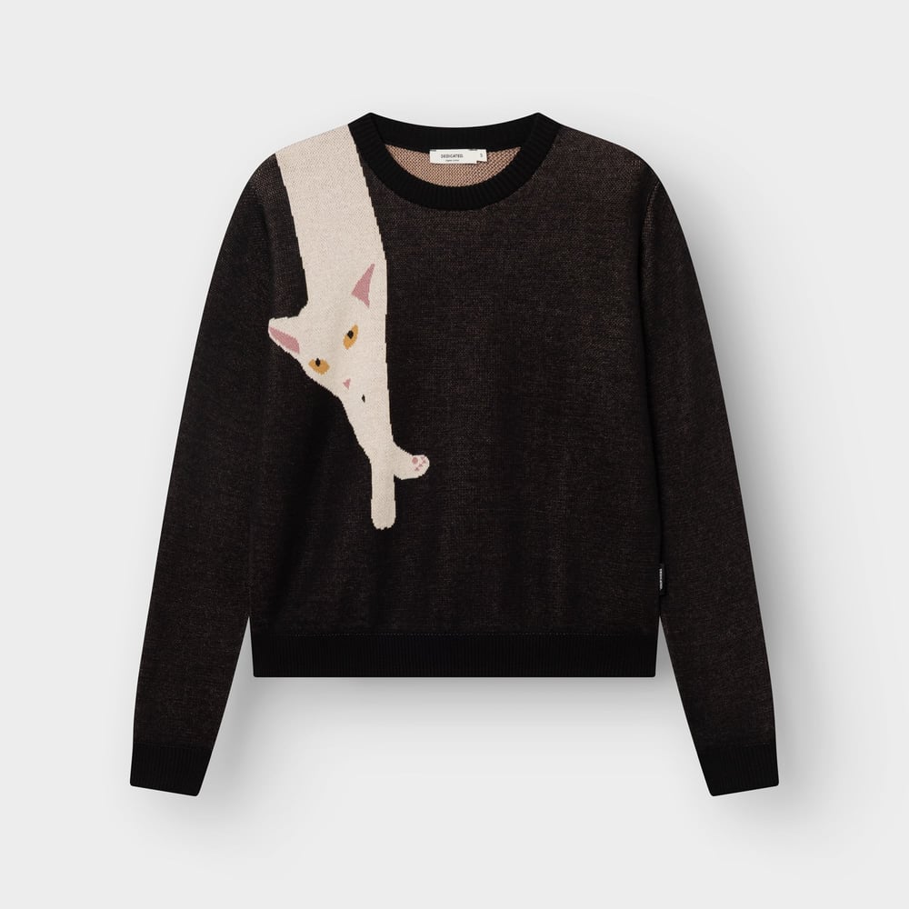 Studio shot of the black Arendal sweater. A long, cream-colored cat with yellow eyes playfully stretches down the front.