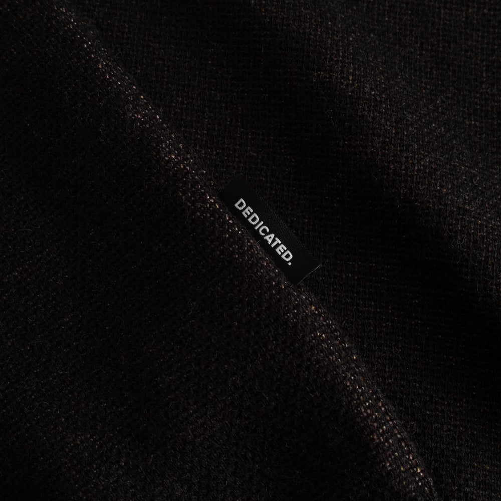 Close-up detail of the Sweater Arendal Long Cat in black, showcasing the jacquard knit texture and the Dedicated brand label.