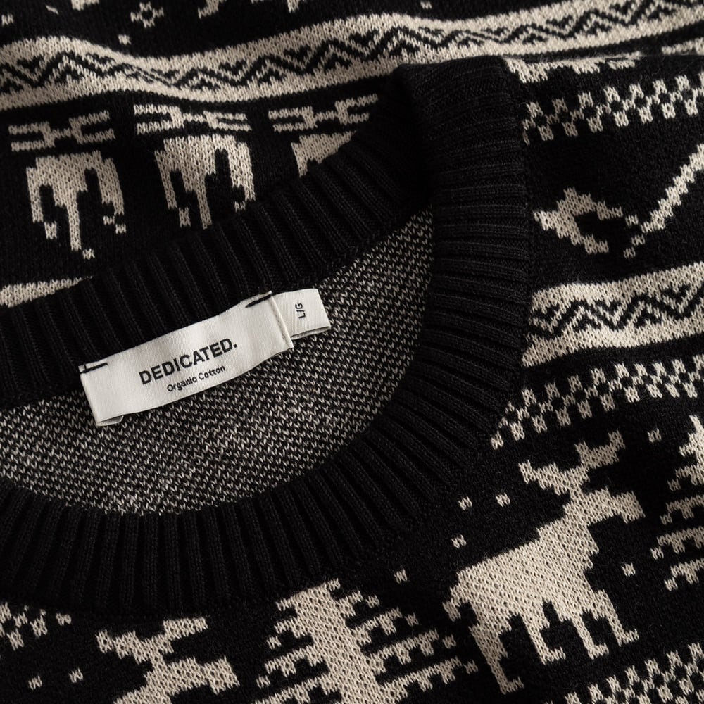 Close-up of the organic cotton Sweater Mora in black, with the intricate Fairisle pattern and the classic Dedicated label.