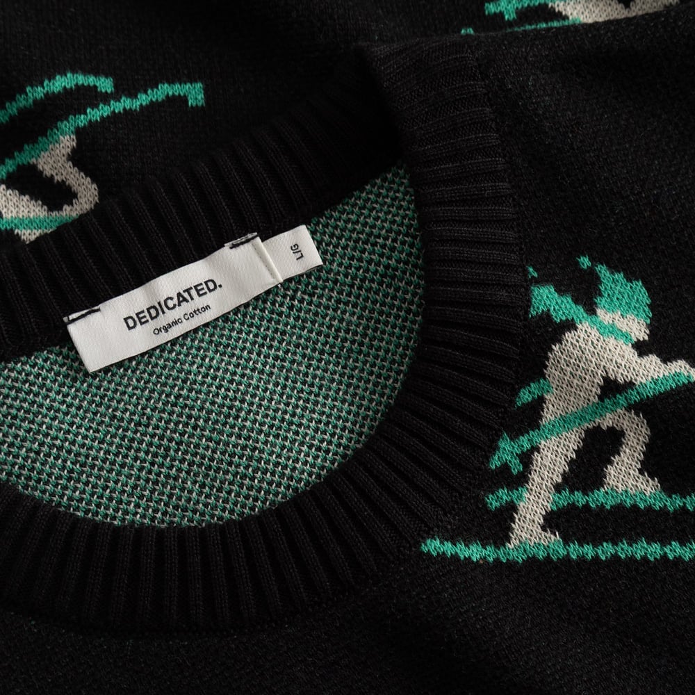Närbild på den svarta stickade tröjan Mora Ditsy Skier som visar den ribbade halsringningen och Dedicateds etikett.
