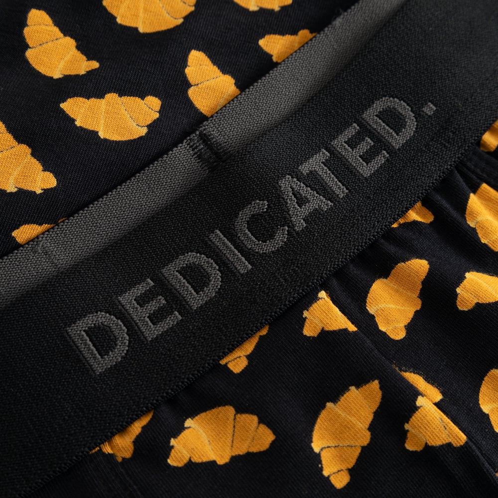 Close-up of the black boxer briefs with a playful croissant print, with its subtle DEDICATED logo on the elastic waistband.
