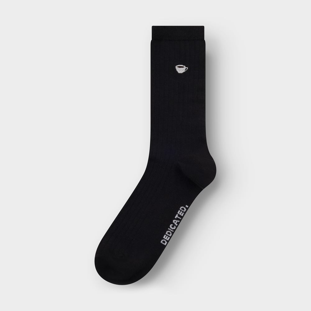Studio photo of a single black ribbed sock from Dedicated, with a small coffee cup embroidered on the ankle.
