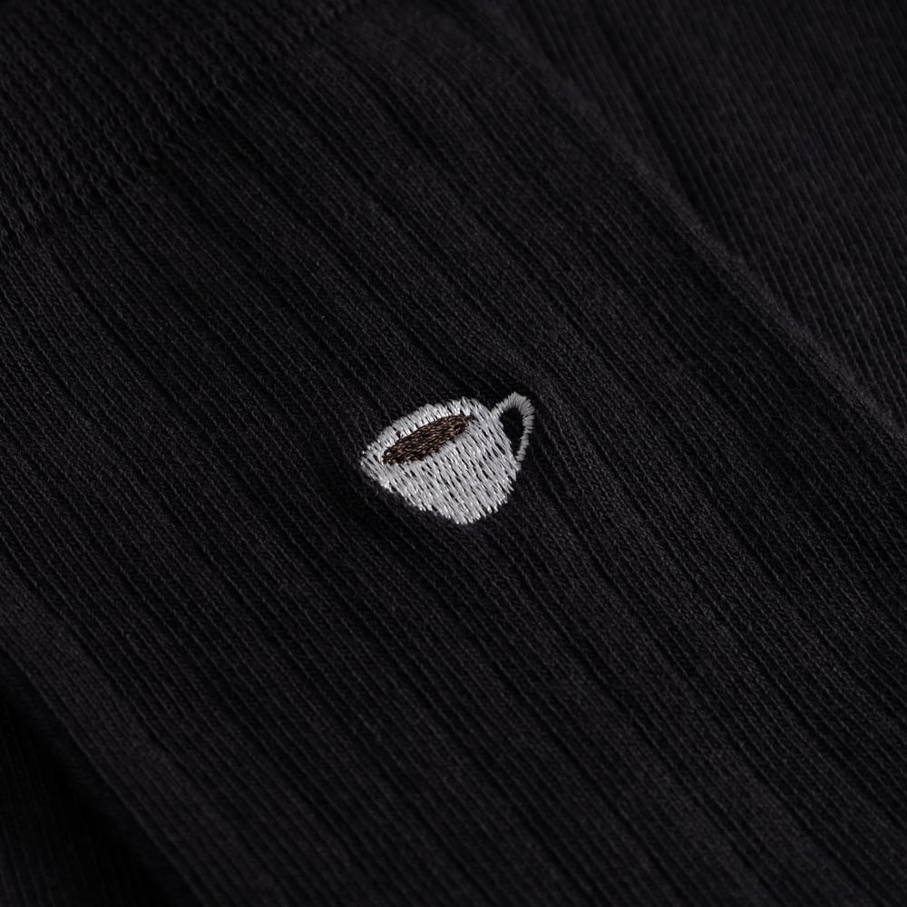 Close-up of the charming coffee cup embroidery on the black ribbed Knivsta socks.
