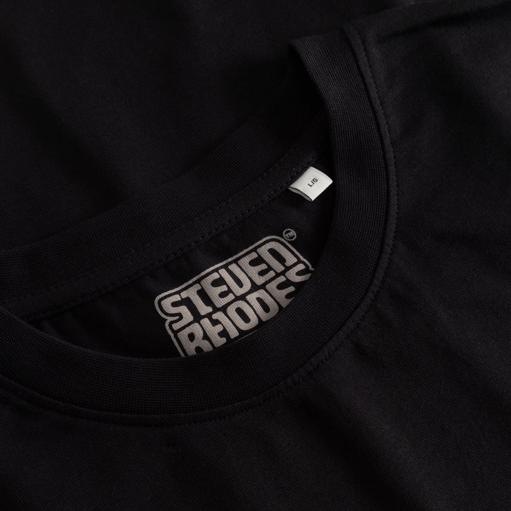 A close-up view of the ribbed neckline of the black Stockholm t-shirt, featuring the Steven Rhodes collaboration label.