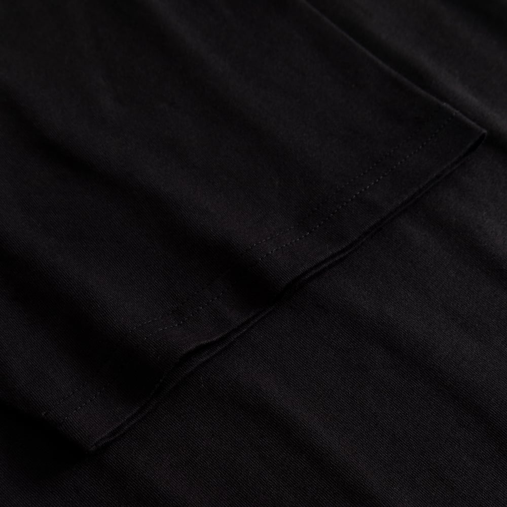 A close-up of the sleeve and stitching detail on the black T-shirt Stockholm Worship Coffee.