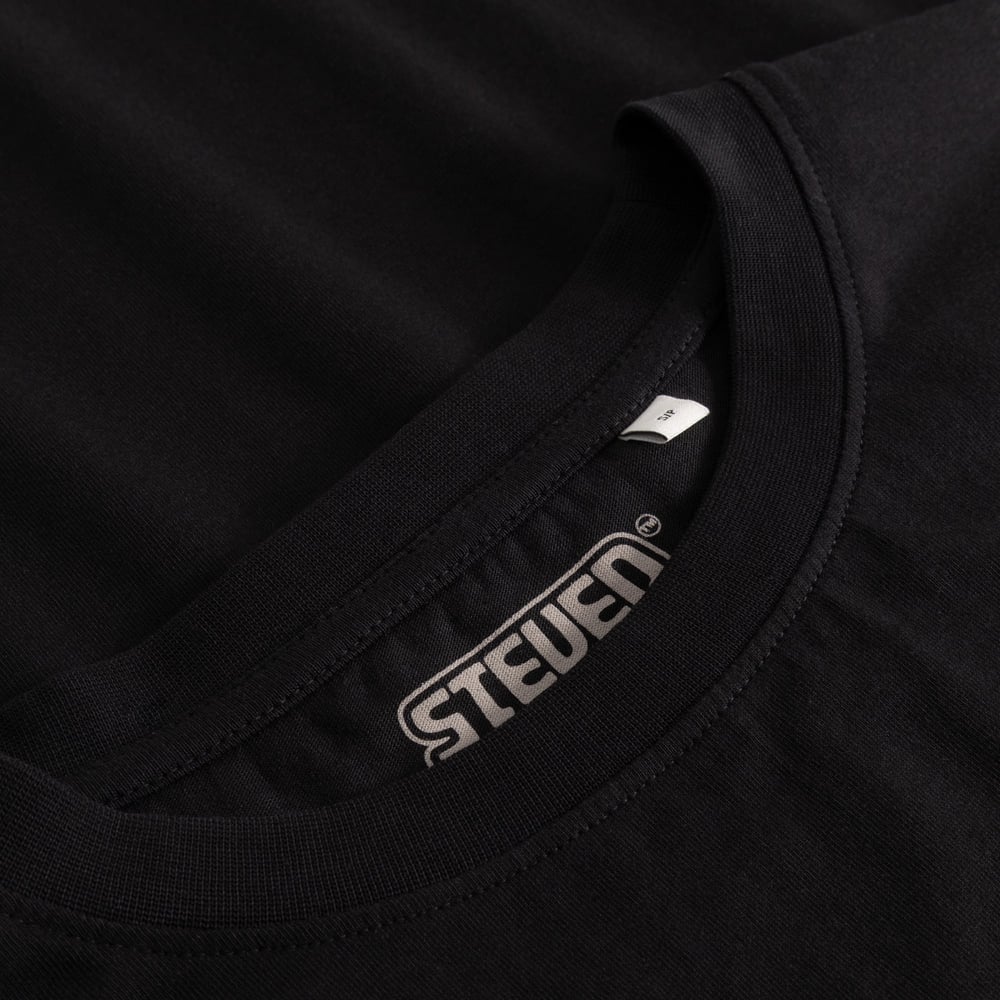 Close-up of the ribbed collar and the printed Steven Rhodes logo inside the black T-shirt Vadstena.