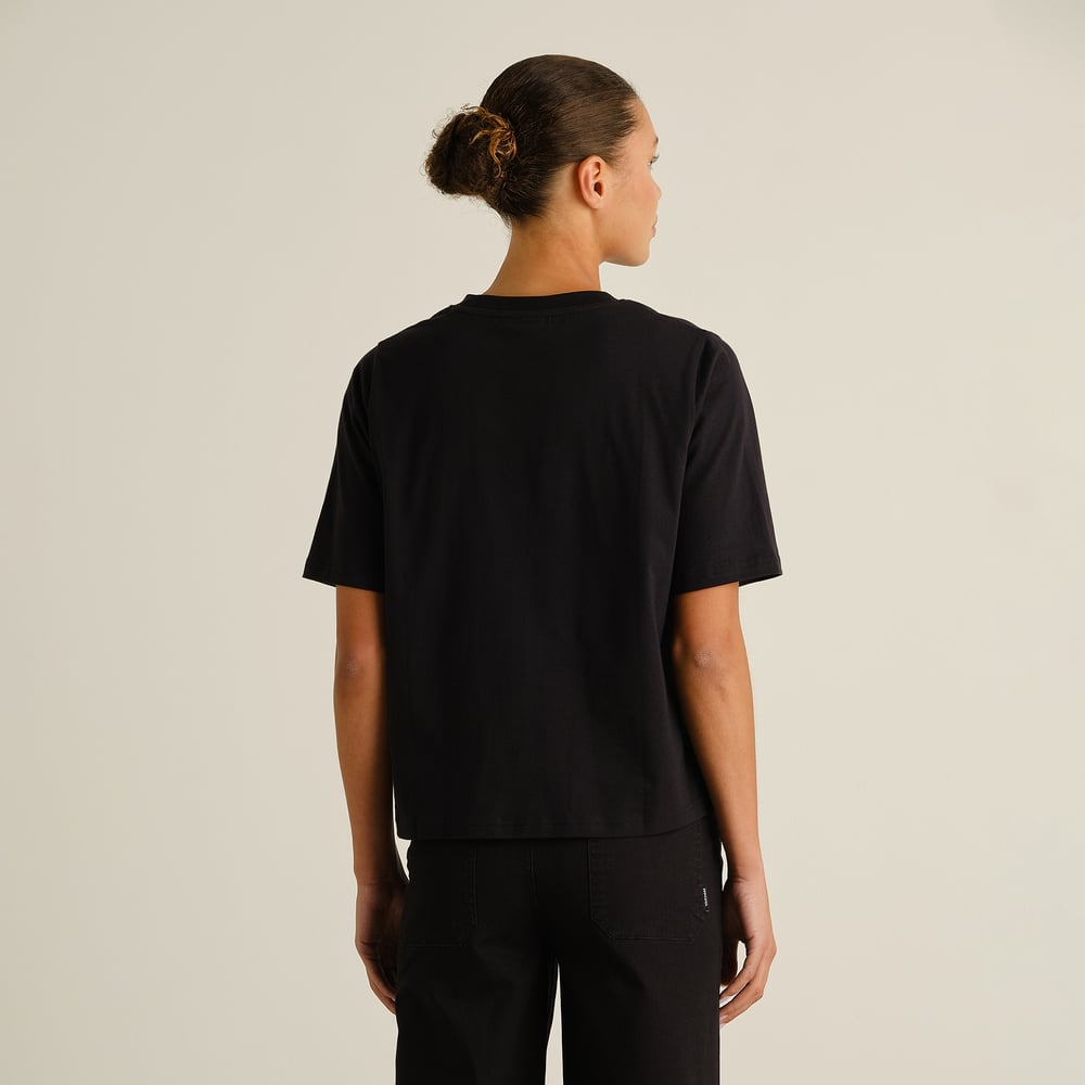 A woman seen from behind wearing the T-shirt Vadstena Painted Swans in black.