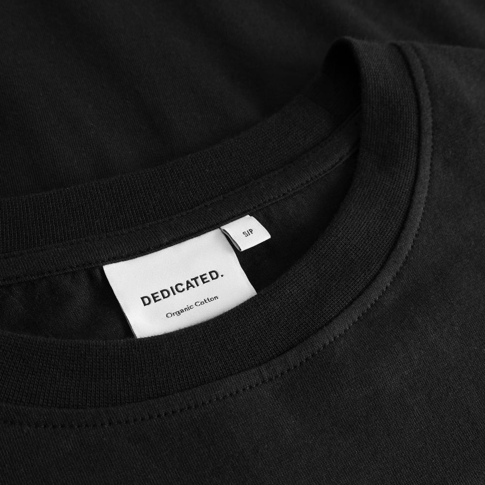 Close-up of the brand label and ribbed crew neck on the black T-shirt Vadstena Painted Swans.