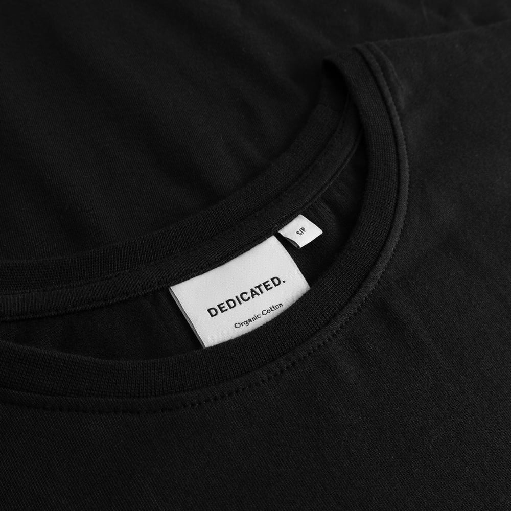 A close-up shot of the ribbed crew neck on the T-shirt Visby Painted Bird, showing the Dedicated brand label.