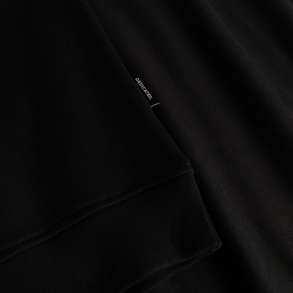 A close-up of the Sweatshirt Ystad in black, highlighting the soft ribbed sleeve cuff and the discreet Dedicated brand tag.