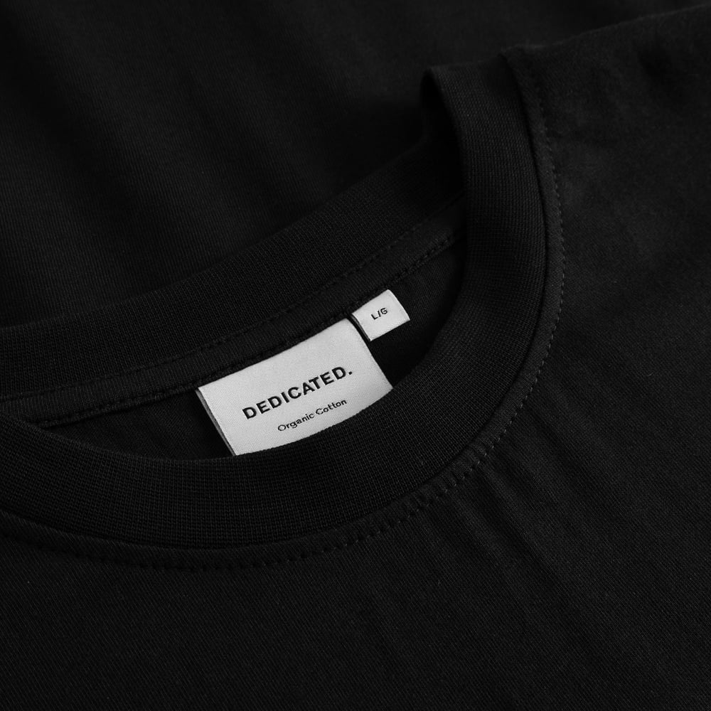 Close-up shot of the Dedicated brand label and ribbed neckline of the black Stockholm Painted Side Bike T-shirt.