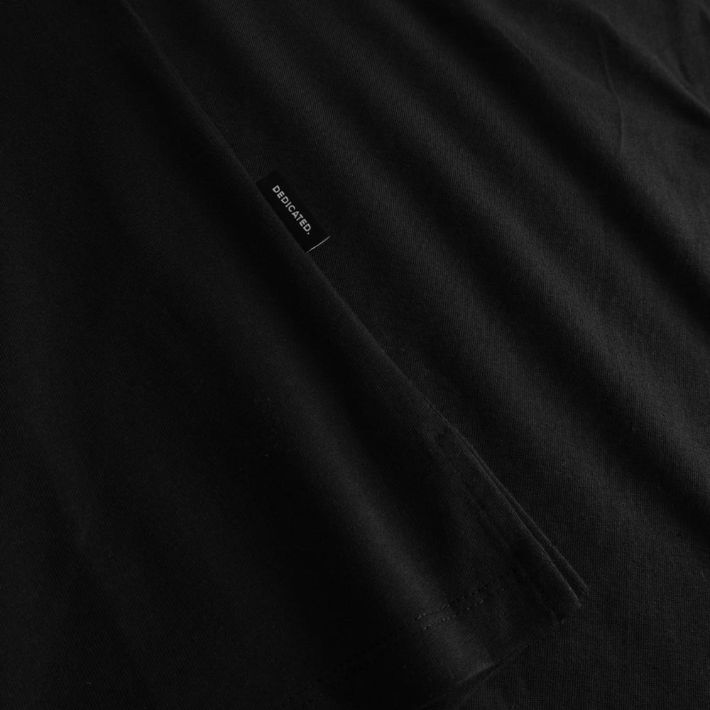 Close-up of the black T-shirt Visby, showing off the neatly folded sleeve, side slit, and a small Dedicated brand tag.