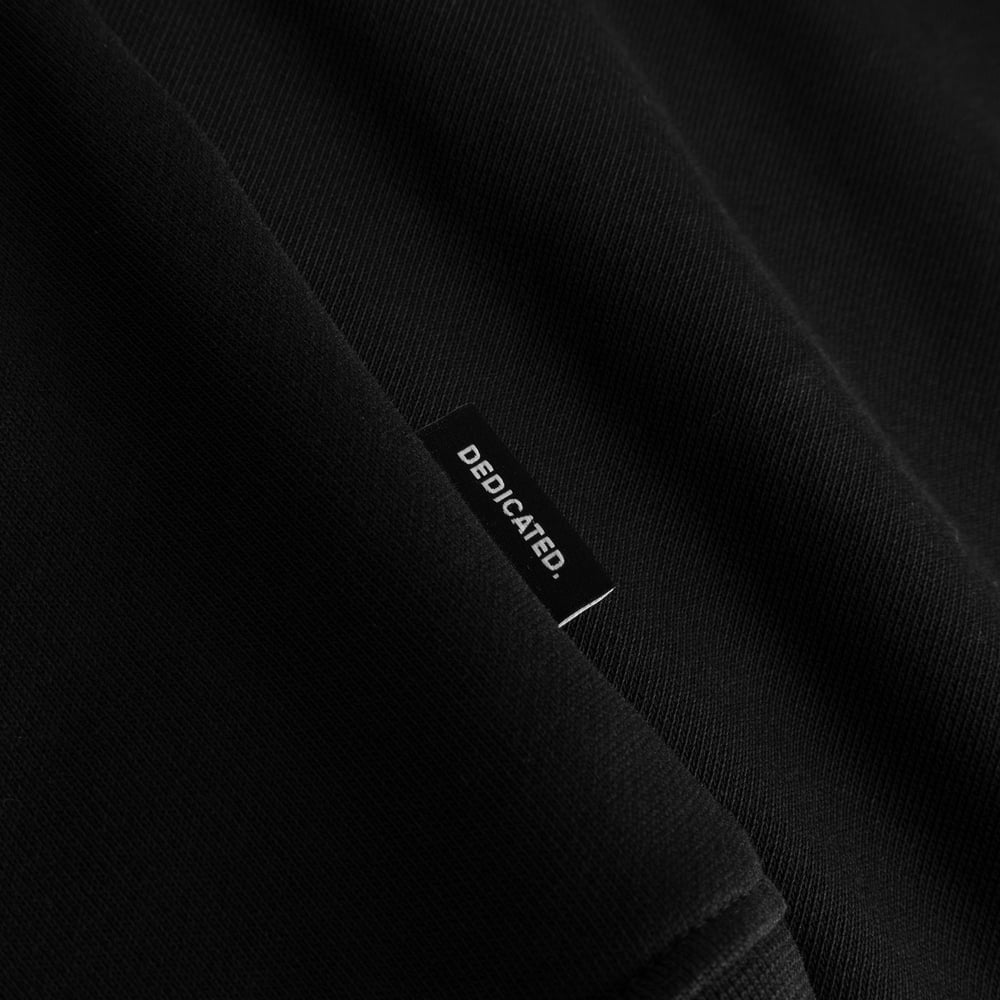 Close-up of the DEDICATED label on the hem of the soft, black organic cotton Sweatshirt Malmoe Perch.