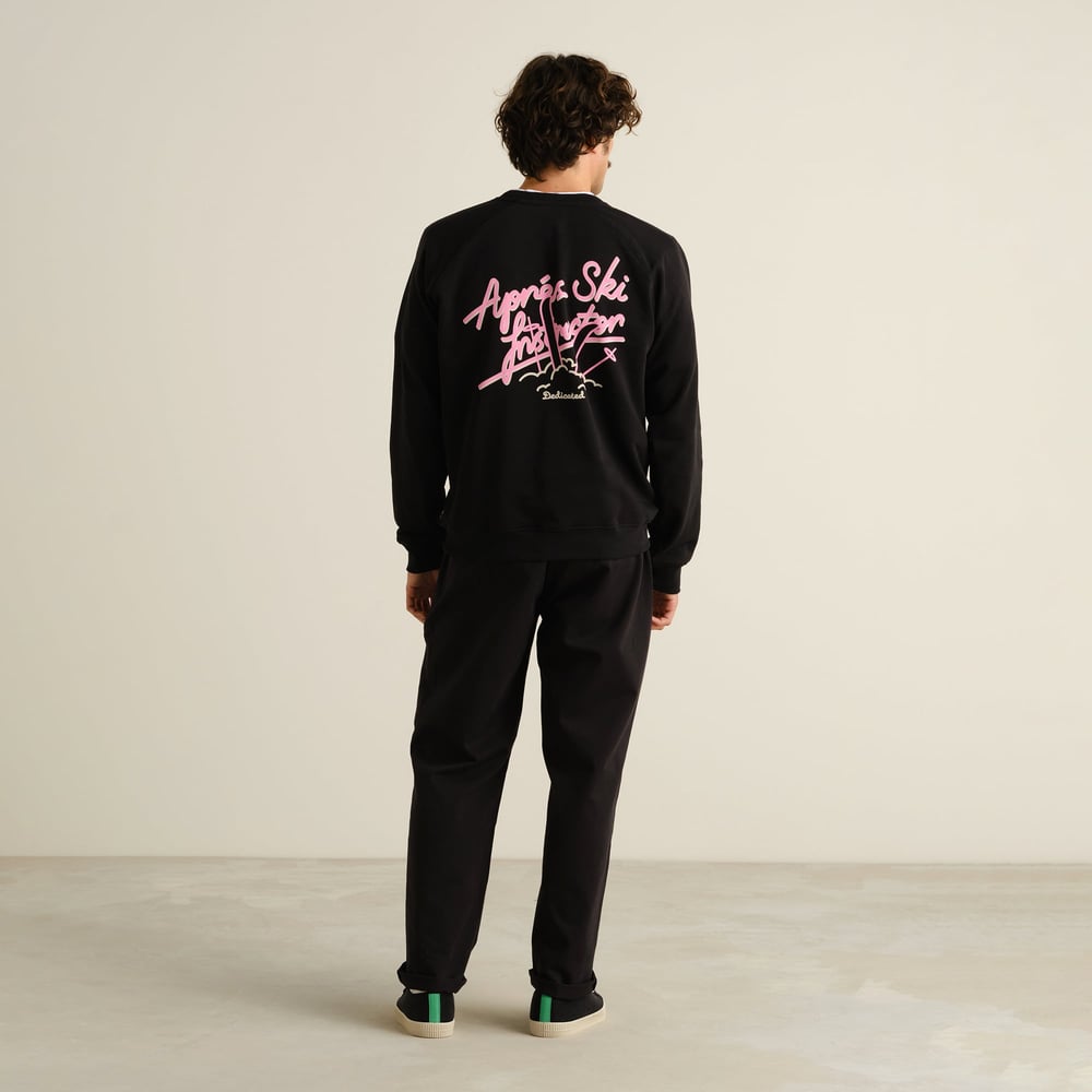A model seen from the back wears the black Sweatshirt Malmoe with its playful pink 'Après Ski Instructor' graphic.