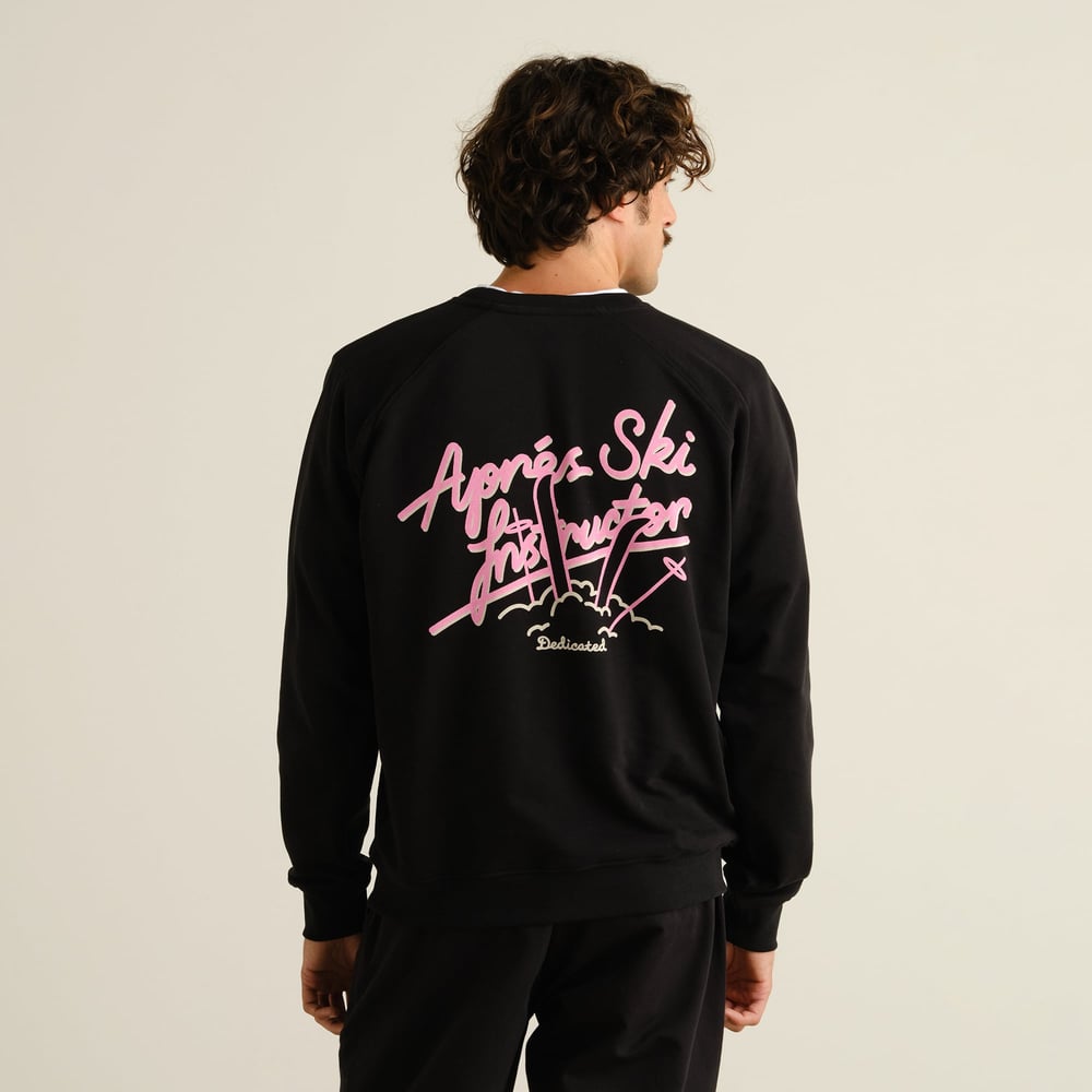 Model seen from the back wearing the black Sweatshirt Malmoe with its pink 'Après Ski Instructor' graphic.