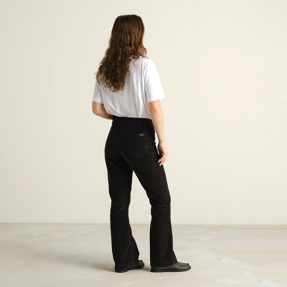 Eine Frau von hinten, die die vorteilhafte Bootcut-Passform der schwarzen Cordhose Ryda zeigt.