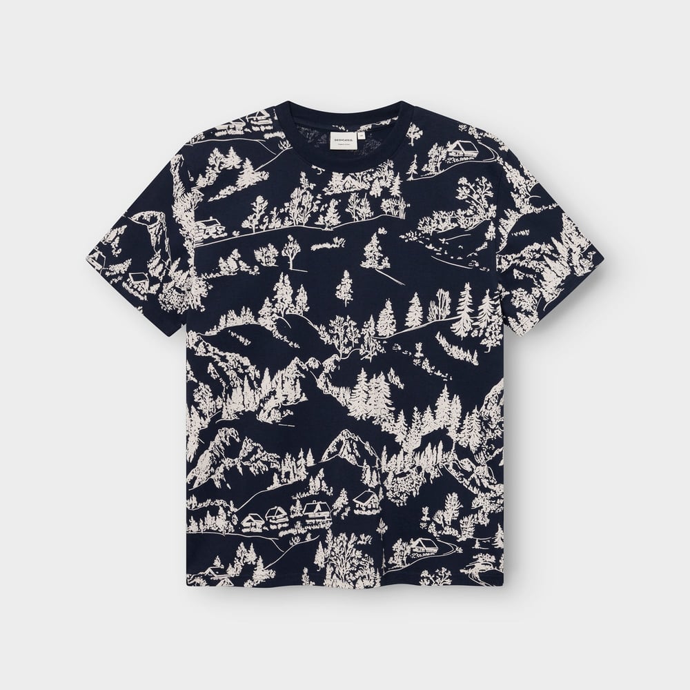 A navy blue t-shirt with a detailed, all-over print of a hillside village surrounded by forests and mountains.