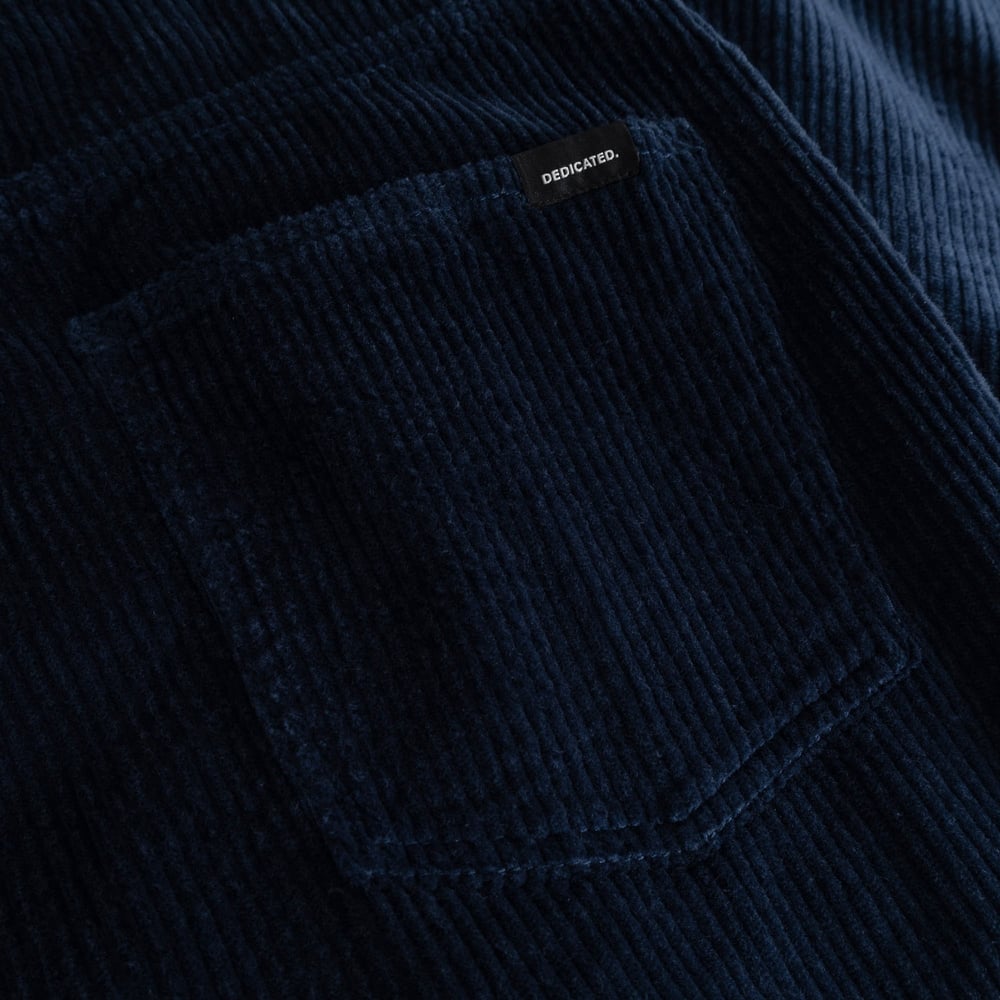 A detailed shot of the rich navy corduroy fabric on the Hamburg pants, with the Dedicated label on the back pocket.