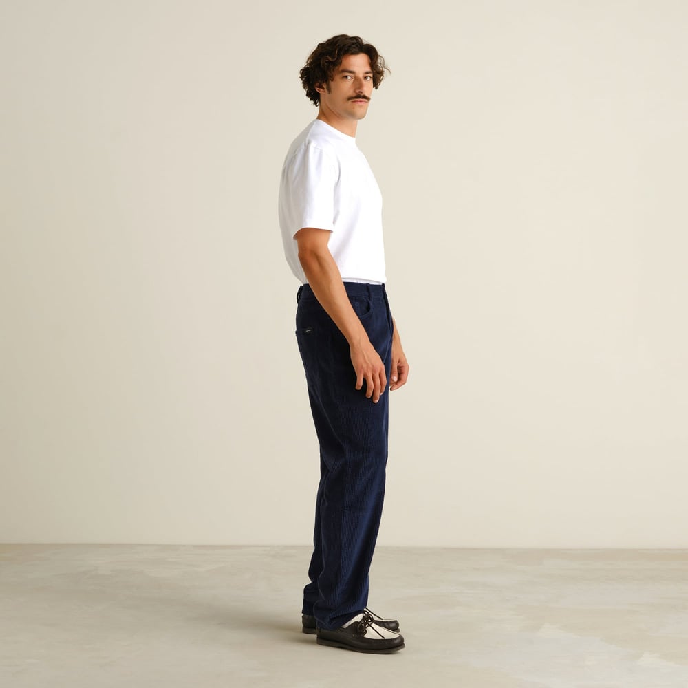 Side profile of a model wearing the relaxed-fit Pants Hamburg Corduroy in Navy with a white t-shirt.