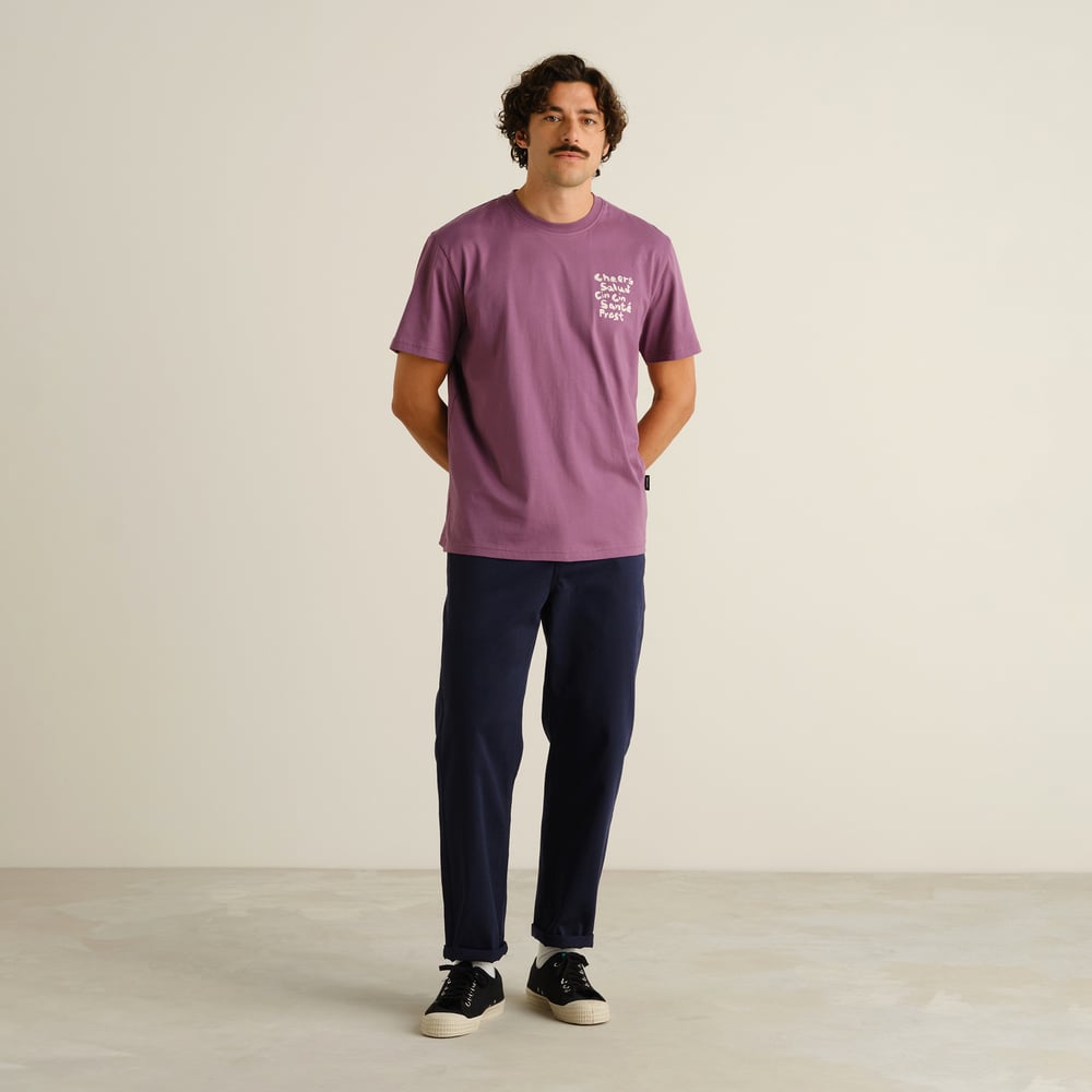 A man styles the navy Chino Pants Hudiksvall with a purple graphic tee and classic sneakers for a relaxed, everyday look.