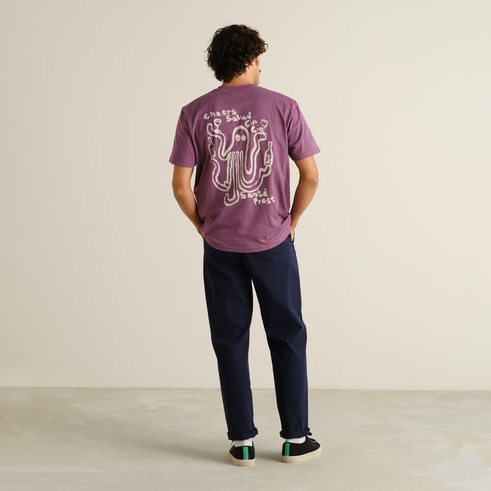 Back view of a man wearing the navy Chino Pants Hudiksvall, styled casually with a purple graphic t-shirt and black sneakers.
