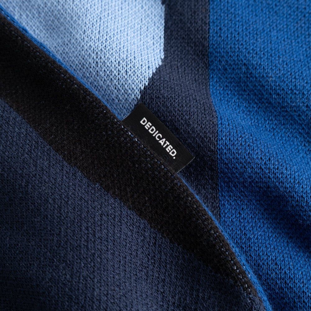 Close-up shot showing the fine knit texture and the black 'DEDICATED.' label on the Sweater Arendal Wavy Stripe Blue.