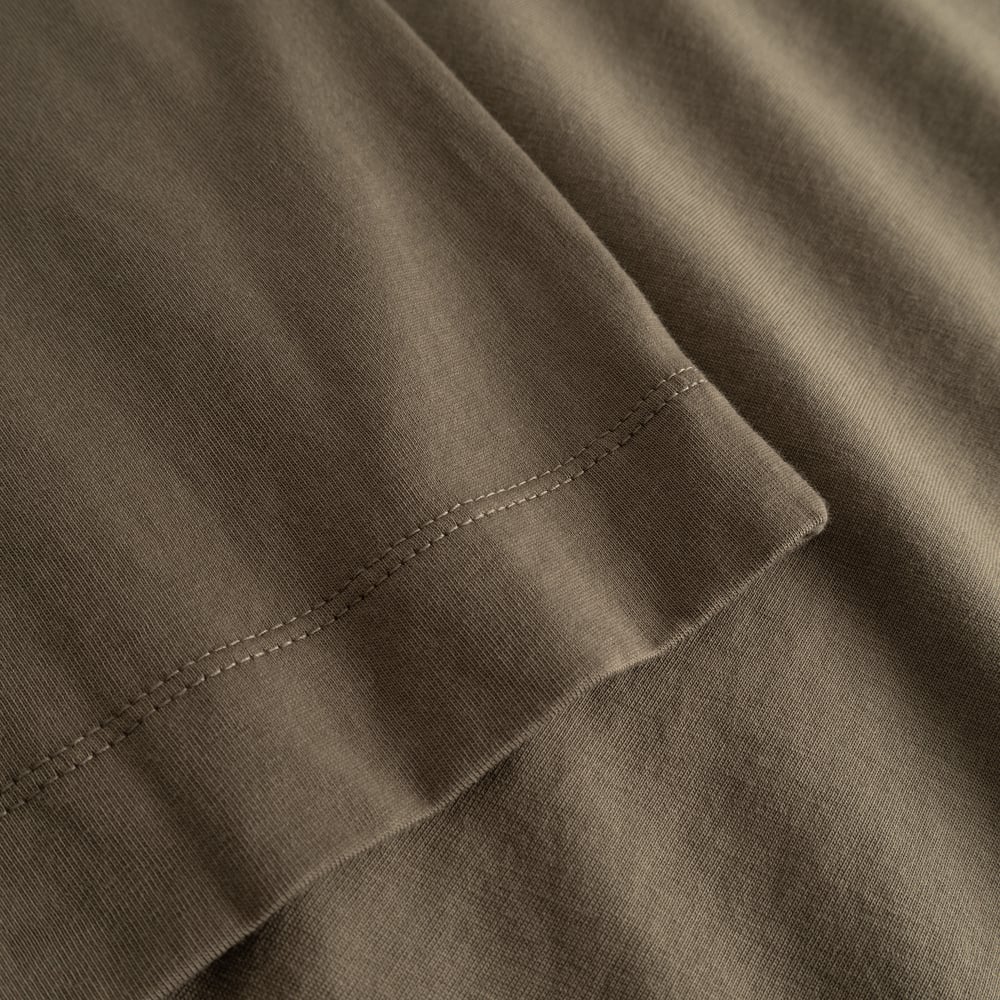 Detailed shot of the Vadstena Base T-shirt's sleeve in Bungee Green, showcasing its soft fabric and quality stitching.