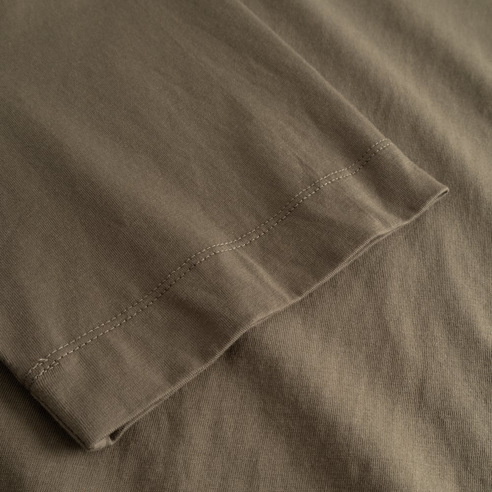 A detailed close-up of the sleeve on the T-shirt Vadstena Base in Bungee Green, showing the fine stitching and fabric.