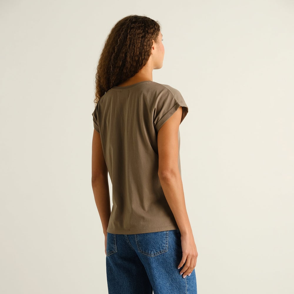 Back view of a woman wearing the slim-fit T-shirt Visby Base in Bungee Green, featuring folded sleeves.