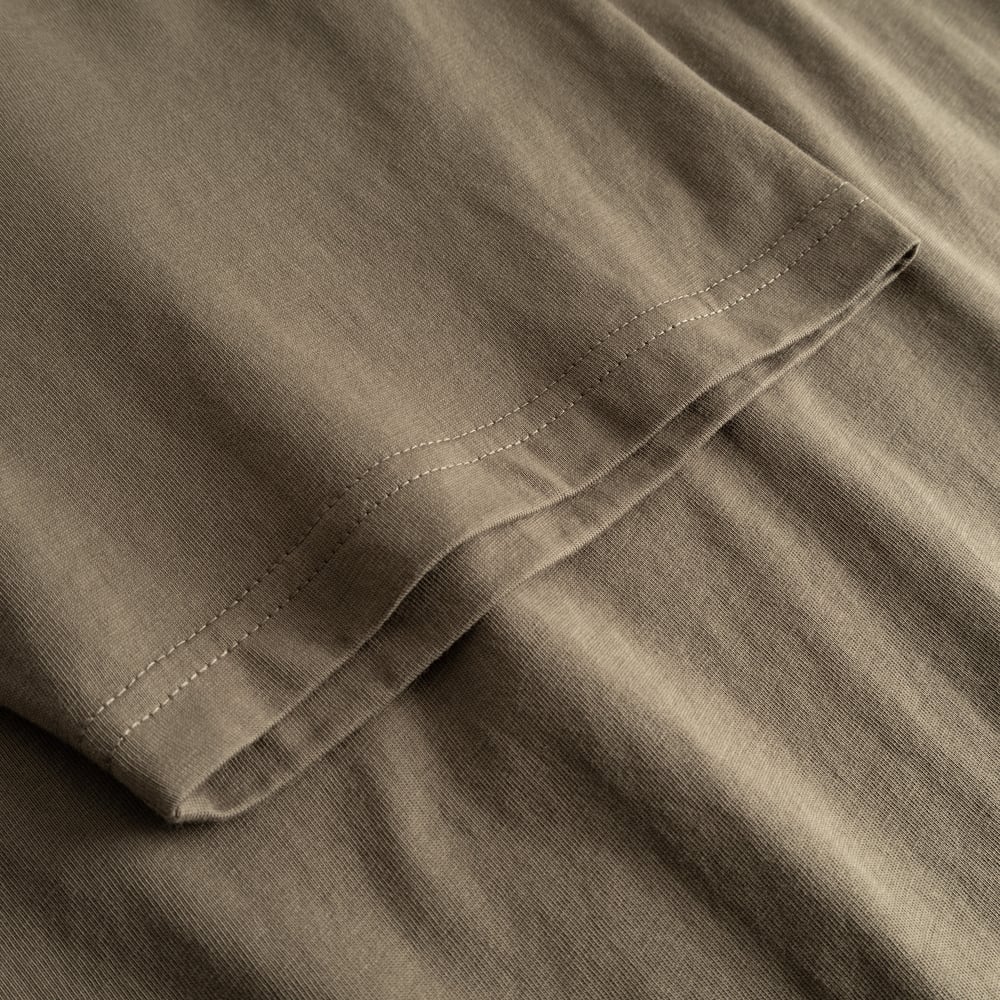 Närbild på ärmen på T-shirt Stockholm Base i Bungee Green, som visar de fina sömmarna och det mjuka bomullstyget.