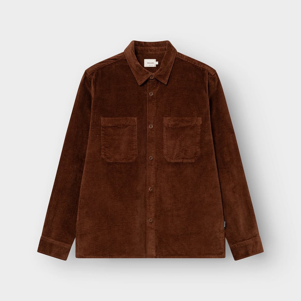 Front view of the Kil Corduroy Overshirt in Cappuccino Brown, laid flat to showcase its classic collar and chest pockets.