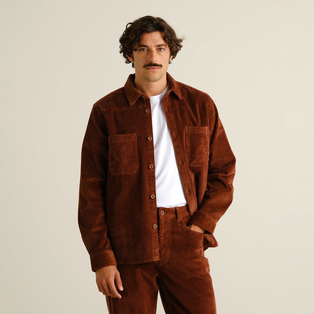 Front view of a model in a stylish cappuccino brown corduroy set, wearing the Kil overshirt layered over a white t-shirt.