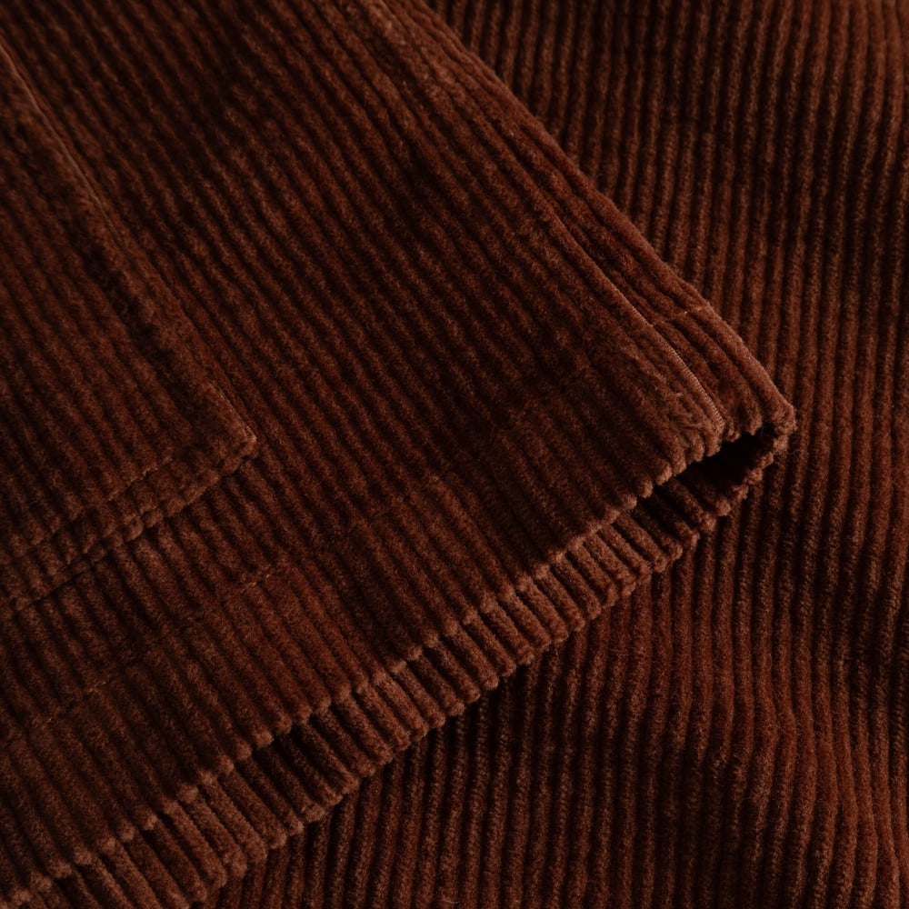 Close-up detail shot of the soft, ribbed corduroy fabric of the Stiby Jacket in a warm cappuccino brown.