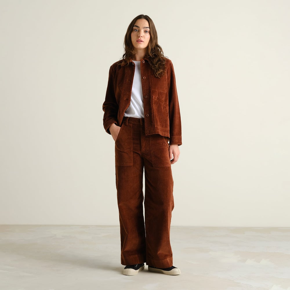 A model rocks a full cappuccino brown corduroy look, featuring the wide-leg Vara Workwear Pants and a matching jacket.