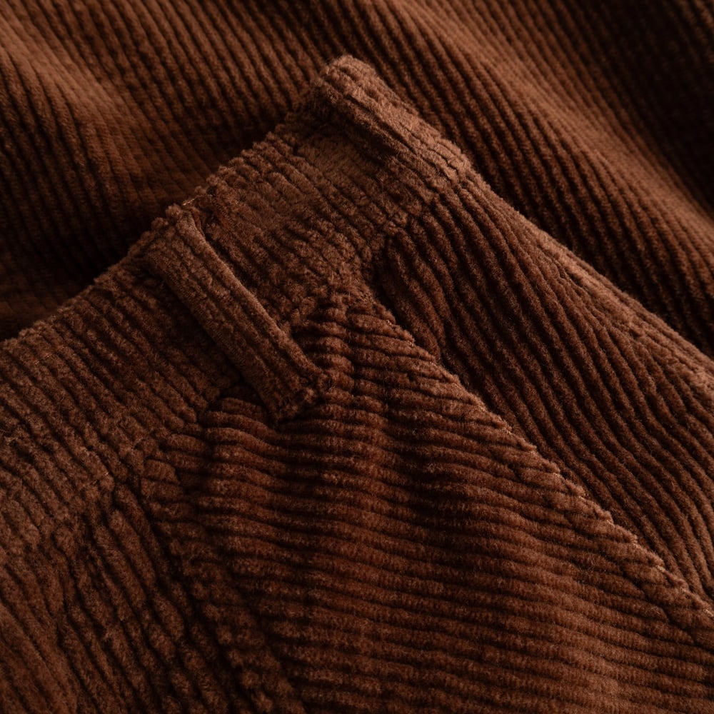 A close-up shot showing the rich texture of the brown corduroy fabric on the Workwear Pants Vara.