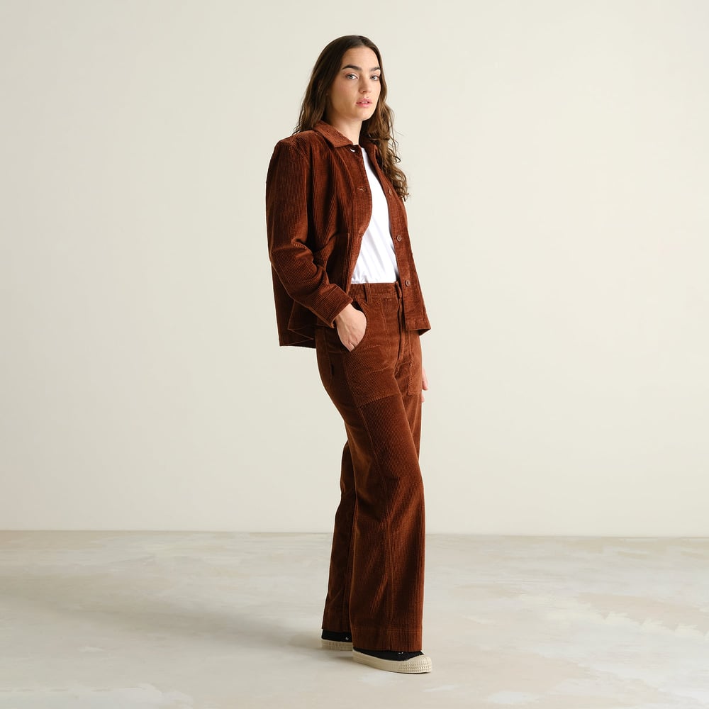A model styles the Vara Workwear Pants in Cappuccino Brown corduroy with a matching overshirt and a simple white tee.