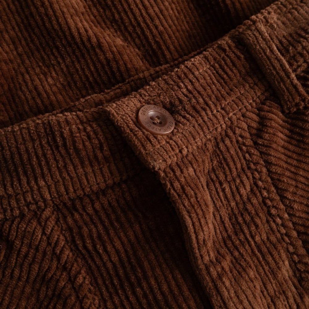 A close-up of the button and rich texture of the Vara Workwear Pants in Cappuccino Brown corduroy.