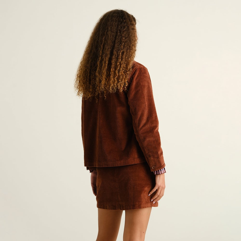 Back view of a model with long curly hair, styling the Skirt Majorna Corduroy in Cappuccino Brown with a matching jacket.