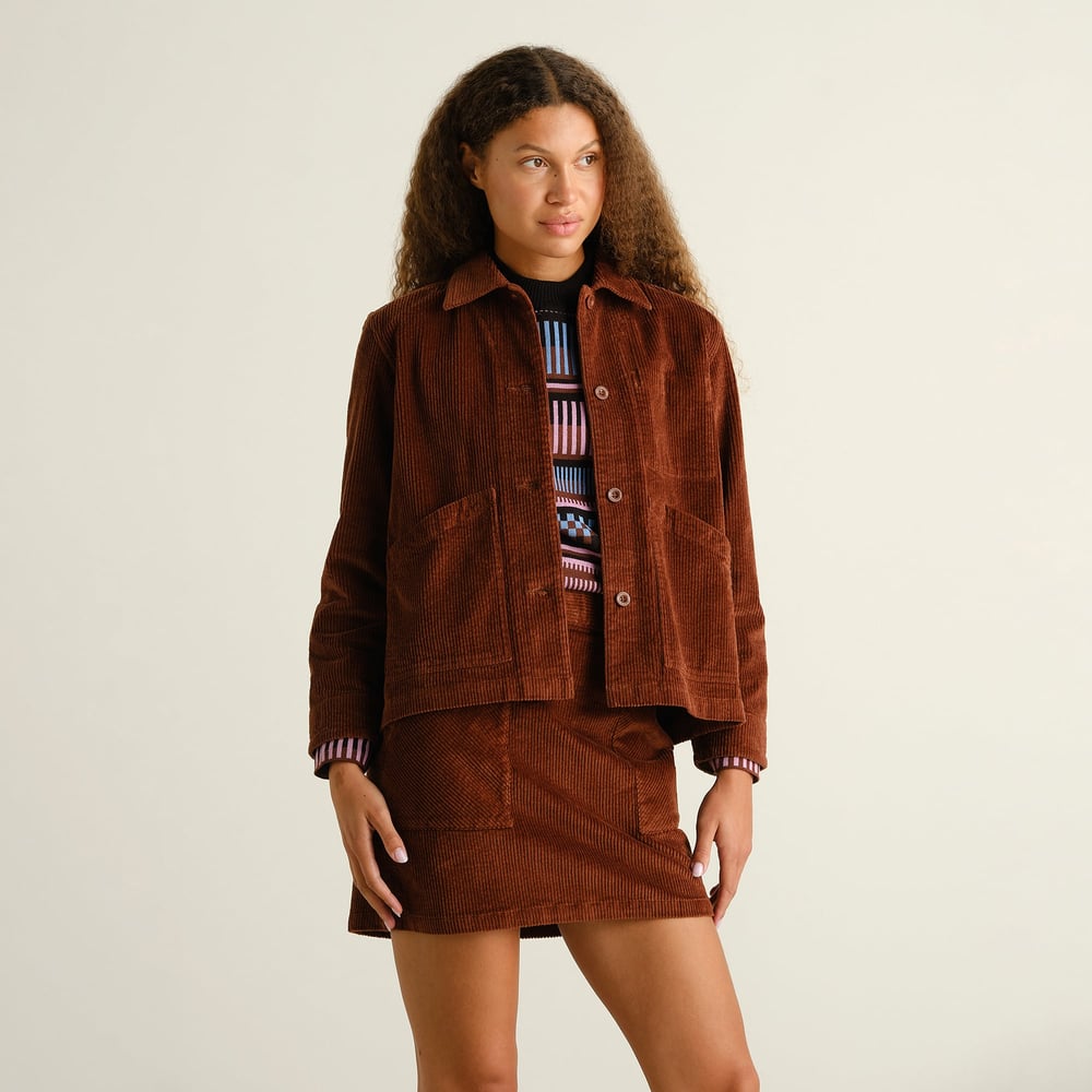 A model looks effortlessly cool in a matching brown corduroy jacket and the Skirt Majorna, layered over a colorful sweater.